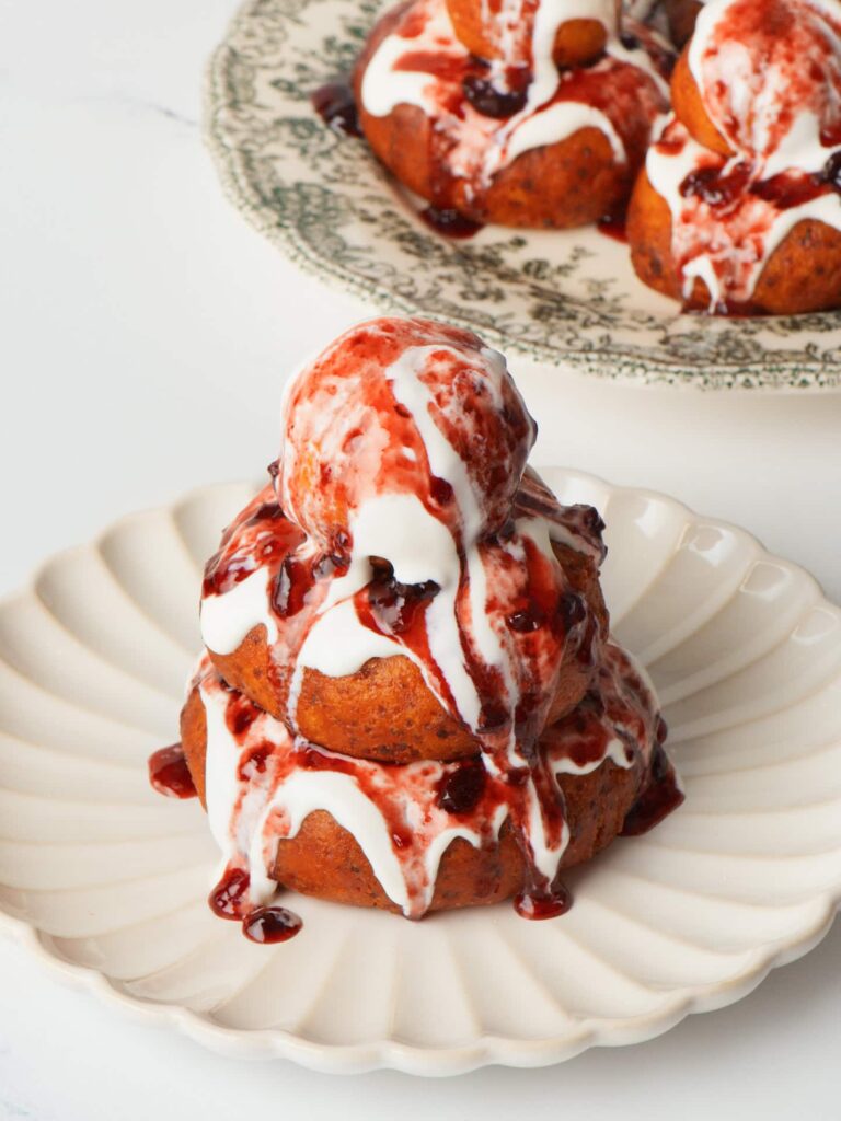 Papanasi plated with two donuts with cream and jam.