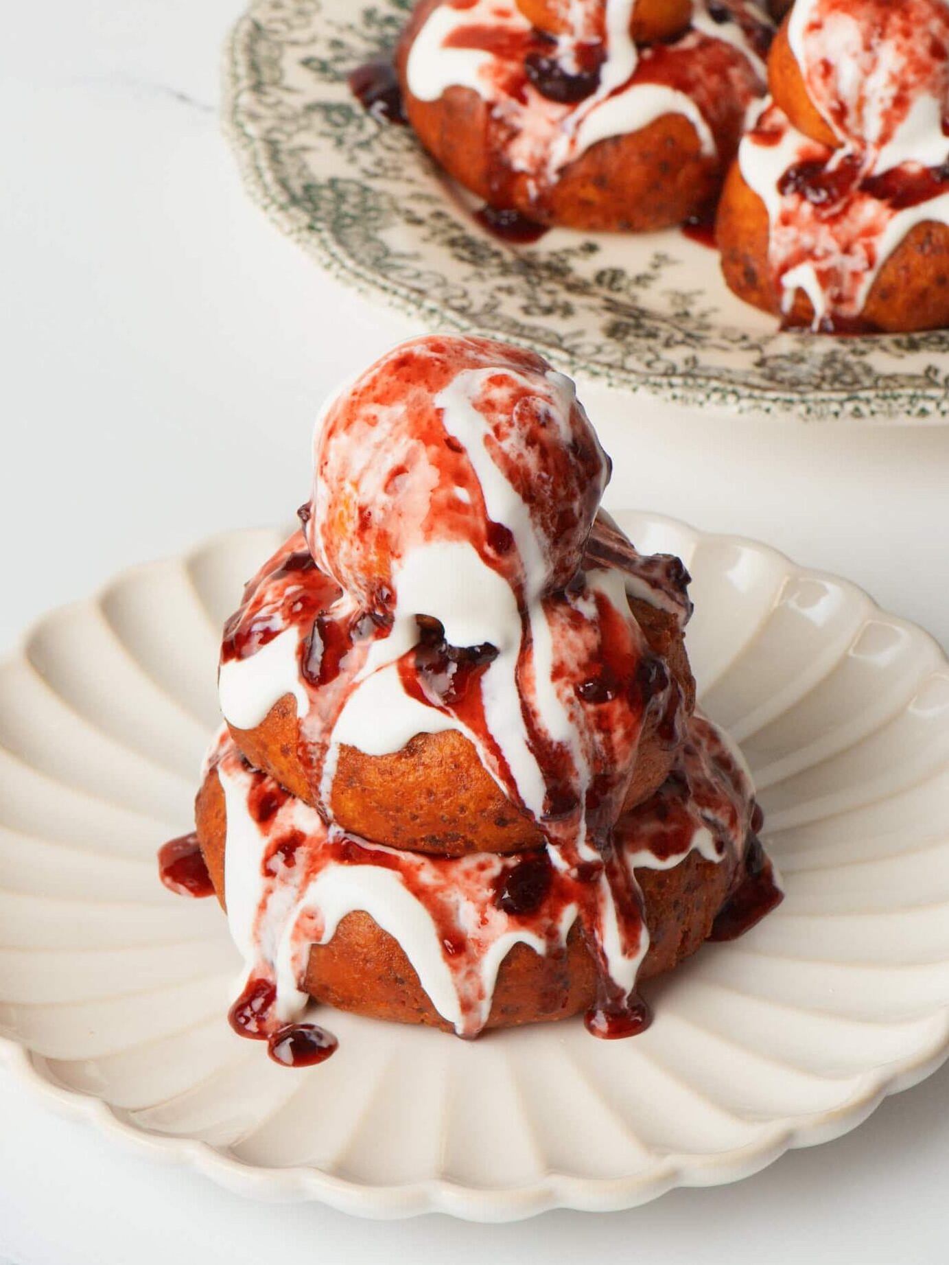 Papanasi plated with two donuts with cream and jam.