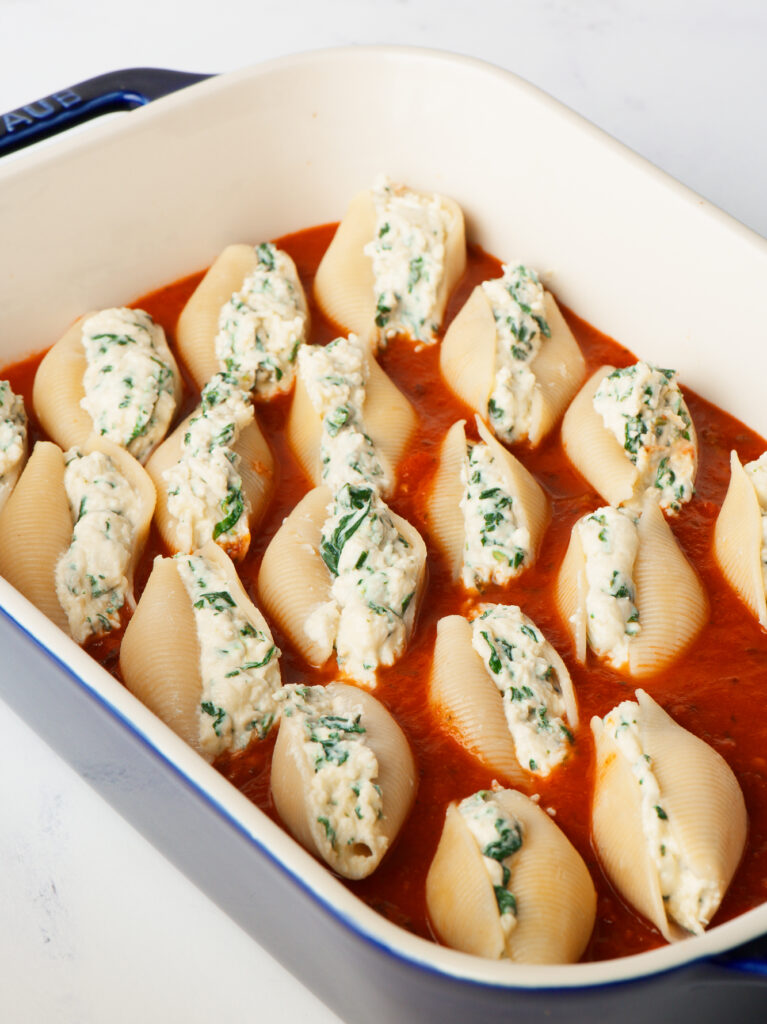 Stuffed Shells in baking dish with marinara.