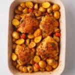 Roasted chicken and potatoes in baking dish.