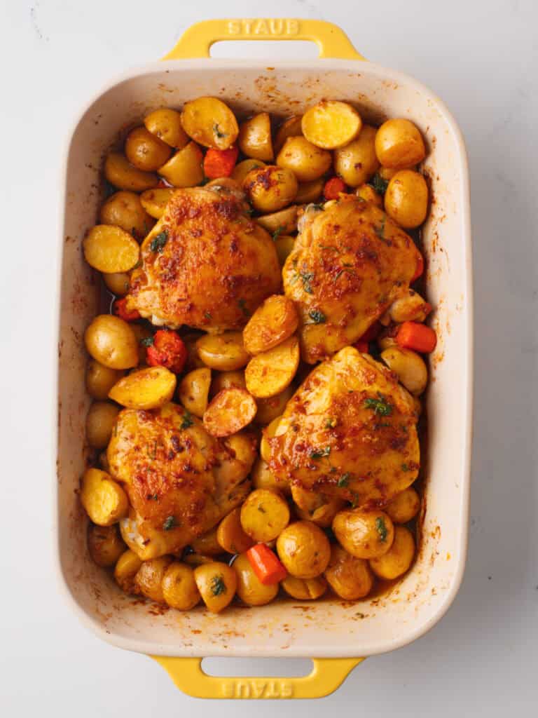 Roasted chicken and potatoes in baking dish.