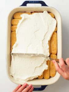 Cream frosting on top of the lady finger layers.