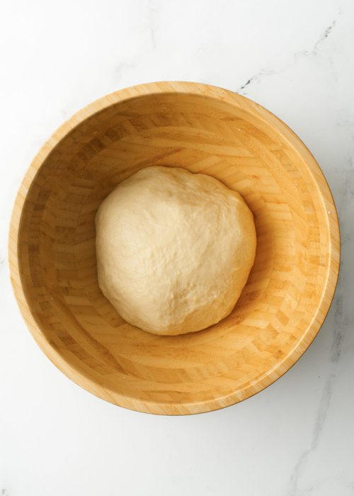 Dough ball in a large wooden bowl.