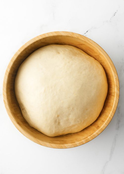 Dough ball in a large wooden bowl.