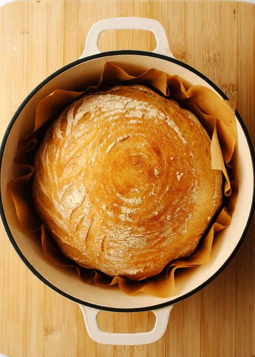 Golden baked artisan bread inside Dutch oven.